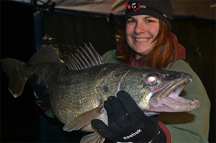Woman holding large walleye at night